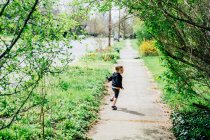 Мальчик бежит по тротуару, оглядываясь через плечо — стоковое фото