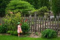 Девушка, нюхающая цветок у огорода — стоковое фото