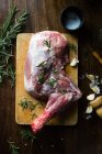 Still life of lamb leg and herbs over chopping board — Stock Photo