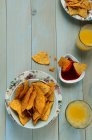 Bol de croustilles, sauce et jus sur la table — Photo de stock