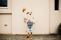 Adorabile bambina che lancia foglie autunnali in aria — Foto stock