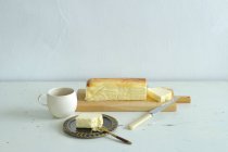 Taza de té y tarta de queso en tablero de madera - foto de stock