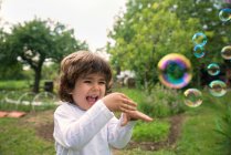 Хлопчик сміється грає з мильними бульбашками — стокове фото