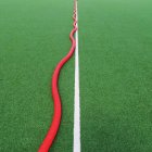 Single white line on green sports field, and red pipe — Stock Photo