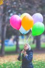 Portrait of a smiling girl holding colorful balloons outdoors — Stock Photo