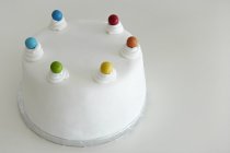 Beautiful tempting fondant covered rainbow cake against white background — Stock Photo