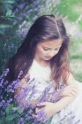 Девушка с длинными волосами сидит на лавандовом поле — стоковое фото