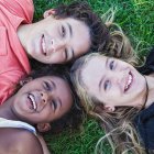 Підліткові багаторасові друзі лежать на землі і сміються — стокове фото