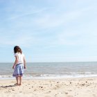Маленькая девочка стоит на песчаном пляже — стоковое фото