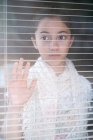 Girl looking through persian blinds at window — Stock Photo