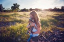 Menina com cabelo longo transportando cão na natureza — Fotografia de Stock