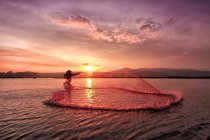 Silhueta de um pescador que captura peixe ao nascer do sol, Lago Rawapening, Java, Indonésia — Fotografia de Stock