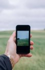 Nahaufnahme eines Mannes beim Fotografieren eines Feldes mit dem Handy — Stockfoto