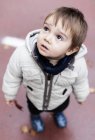 Маленький хлопчик в куртці дивиться вгору — стокове фото