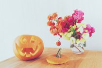 Halloween-Konzept, Jack-o-Laterne, Kürbis und Blumen — Stockfoto