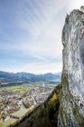 Hombre escalada en roca por encima de la ciudad, Hallein, Salzburgo, Austria - foto de stock