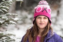 Smiling girl standing in forest in snow — Stock Photo
