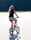 Visão traseira da mulher andando de bicicleta dobrável no parque — Fotografia de Stock