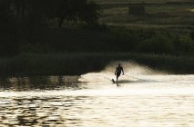 Silhouette di un uomo che si sveglia sul lago al tramonto — Foto stock