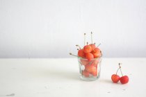 Glas frische Kirschen auf weißem Hintergrund — Stockfoto