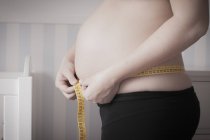 Imagem cortada de mulher grávida medindo barriga — Fotografia de Stock