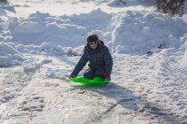 Menino ajoelhado no trenó na neve no inverno — Fotografia de Stock