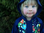Retrato de una niña rubia sonriente con chaqueta encapuchada - foto de stock