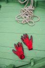 Повышенный вид красных перчаток и веревки на рыбацкой лодке — стоковое фото