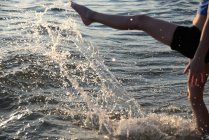 Imagen recortada de Chica salpicando en el agua en la playa - foto de stock