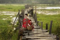 Портрет женщины в традиционной тайской одежде, сидящей на мосту — стоковое фото