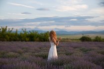 Woman wearing white dress standing in a lavender field — Stock Photo