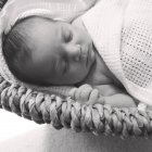 Baby girl sleeping in basket under blanket — Stock Photo