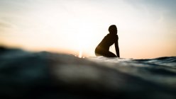 Silhouette einer Frau, die auf einem Surfbrett im Ozean sitzt, Malibu, Kalifornien, Amerika, USA — Stockfoto