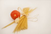 Spaghetti, tomato and garlic composition, beige background — Stock Photo