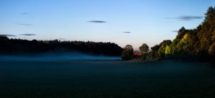 Захід сонця через туманні сільськогосподарські угіддя під блакитним небом — стокове фото