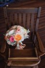 Bouquet de mariage coloré sur chaise en bois — Photo de stock