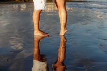 Low-section of young couple standing on beach — Stock Photo