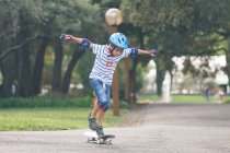 Junge mit Helm skateboardet im Park — Stockfoto