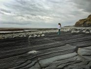 Chica de pie en la playa, Kilve, Costa Jurásica, Somerset, Inglaterra, Reino Unido - foto de stock