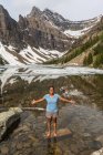 Chica afroamericana de pie con los brazos extendidos, Lago Agnes, Parque Nacional Banff, Alberta, Canadá - foto de stock