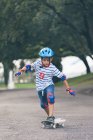 Хлопчик в шоломі скейтбординг у парку — стокове фото