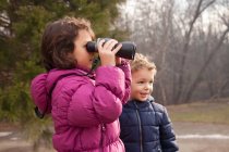 Menina olhando para binocular na floresta de inverno — Fotografia de Stock