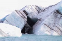Icebergs listrados pretos flutuando na lagoa Joekulsarlon, Islândia — Fotografia de Stock