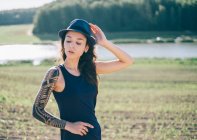 Hipster Mulher com manga de tatuagem em pé na paisagem rural — Fotografia de Stock