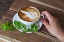 Abgeschnittenes Bild einer Frau mit einer Tasse Cappuccino — Stockfoto