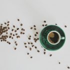 Кавові зерна та чашка кави на білому тлі — стокове фото
