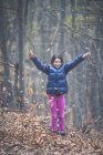 Девушка бросает осенние листья в воздух в лесу — стоковое фото
