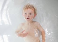 Вид сверху на симпатичного мальчика, лежащего в ванне — стоковое фото