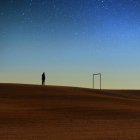 Silueta del hombre de pie en la colina contra el cielo nocturno - foto de stock