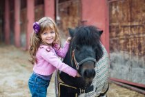 Portrait de petite fille étreignant poney — Photo de stock